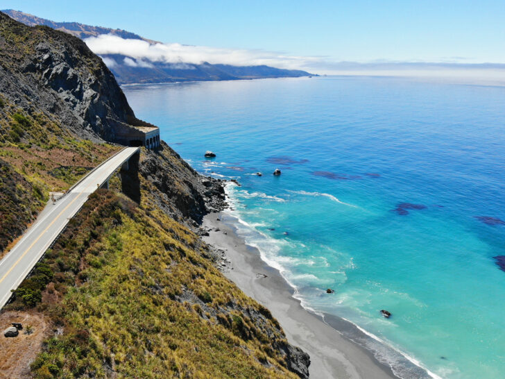 west coast road trip USA view of ocean and road with black sand beach and rugged coastline