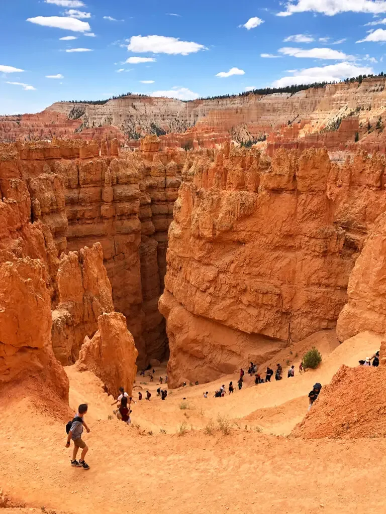 Wall Street Bryce Canyon view of people hiking down zig zag trail with orange rocky spires into canyon