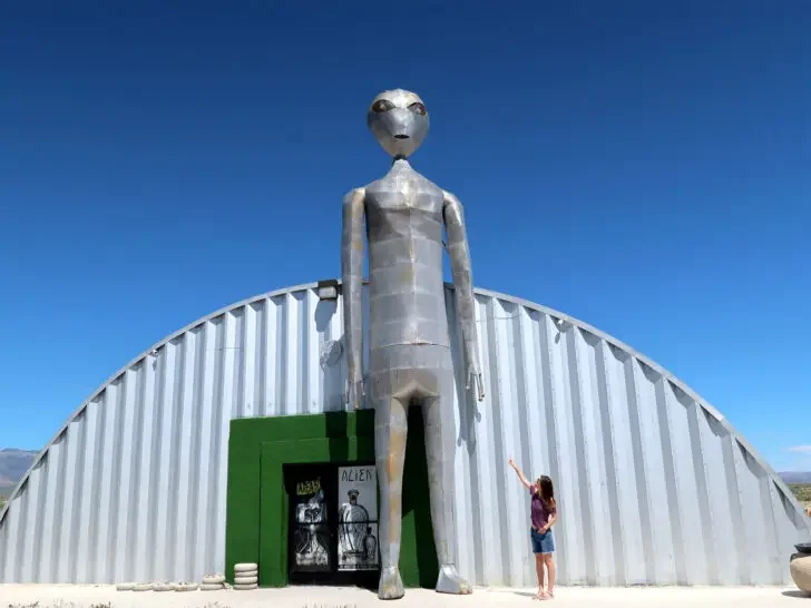 road trips USA view of large metal alien at metal building with woman on a road trip through Nevada