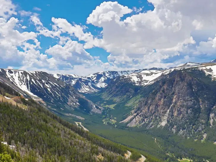 road trips USA view of mountains with green valleys and white snowy tops on cloudy day along beartooth highway