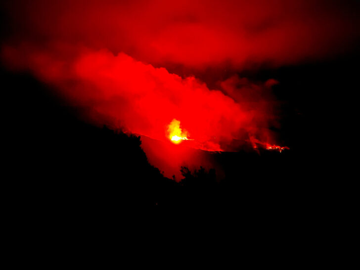 best national parks to visit in may view of volcano lava at night with red sky