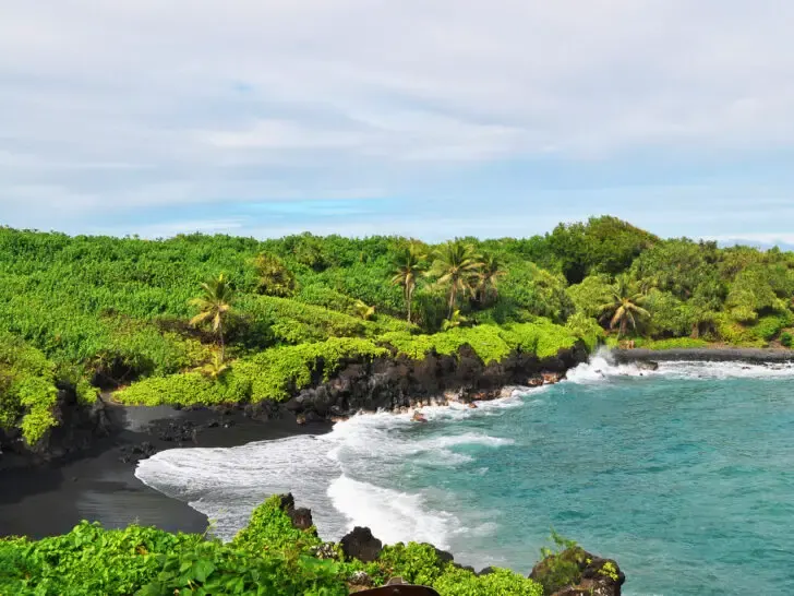 road trips USA new of black sand beach green foliage and blue water in Road to Hana Maui