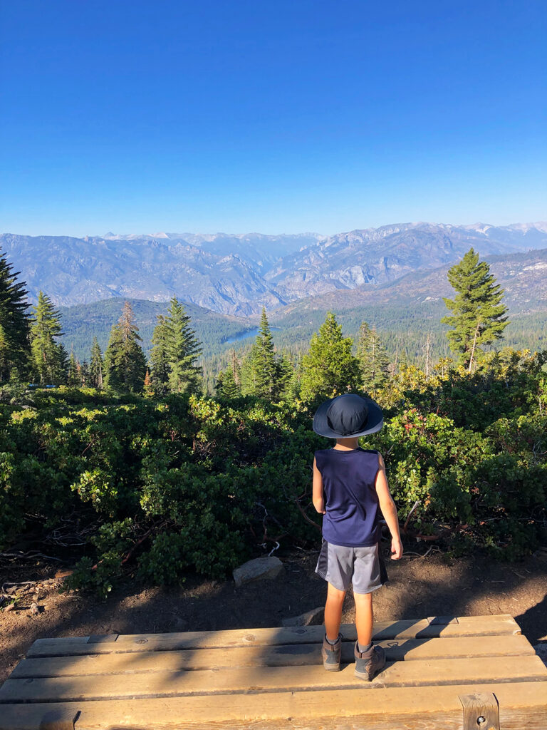 kid standing on bench overlooking Sierra Nevada mountain range