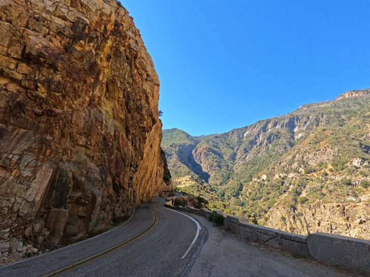 scenic drive through canyon with tall cliffs and green mountainside