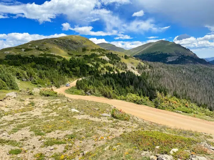 bucket list colorado view of old Fall River road through mountains on partly sunny day with green trees and hillside