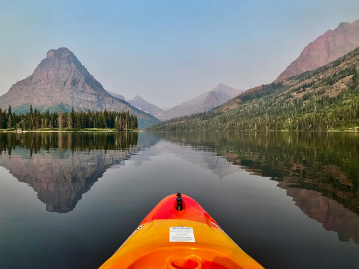 national parks with kids view of orange kayak on water with reflective mountain in distance