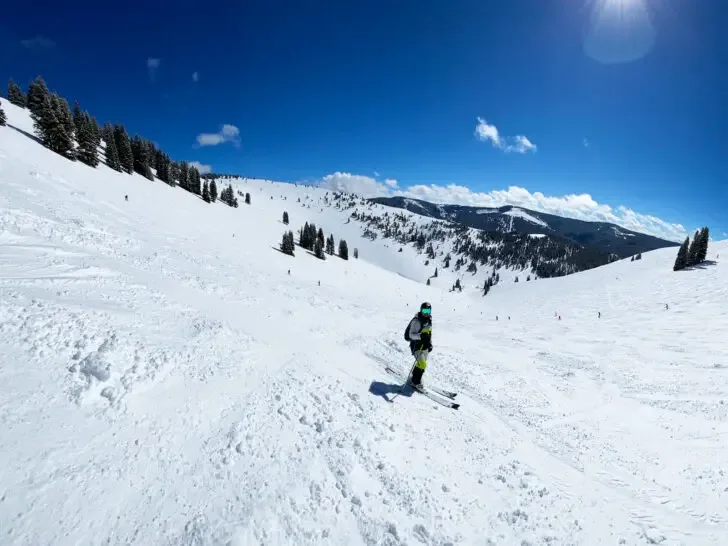 snowy mountain with skier and blue sky