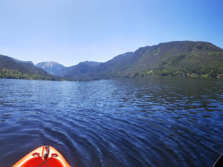 kayaking on grand lake colorado view with orange kayak tip blue water and mountains in the distance