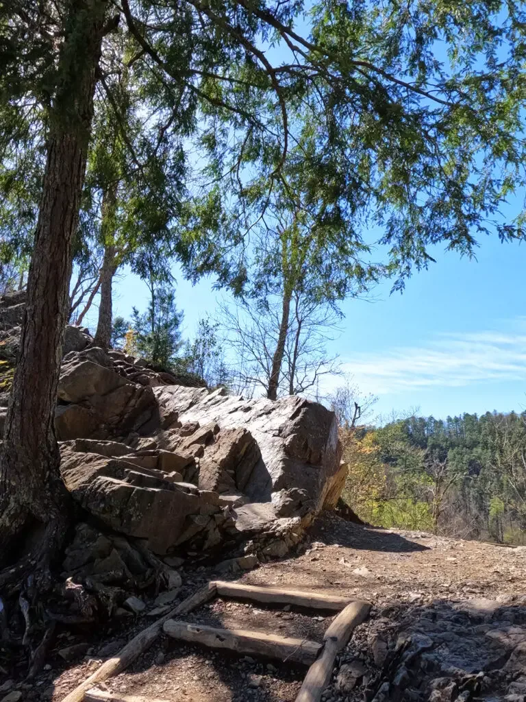 Abrams Falls Smoky Mountains view of dirt hiking path past large boulders with green trees in distance