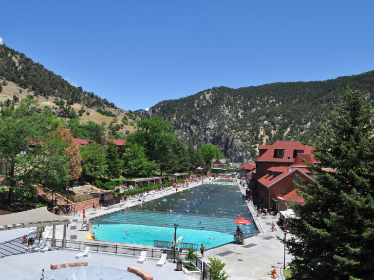 large hot springs swimming pool with canyon and buildings surrounding it