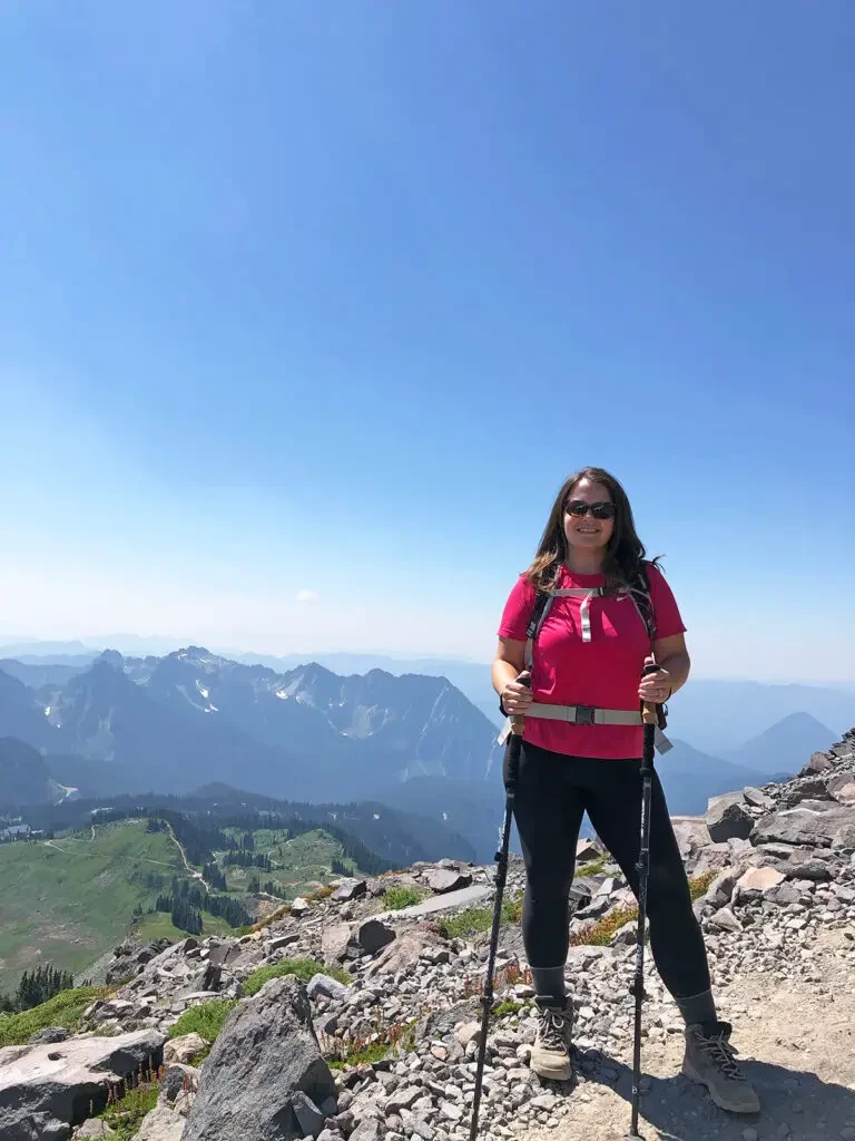 paradise trail mt rainier woman in pink shirt standing on mountain top with mountains in distance