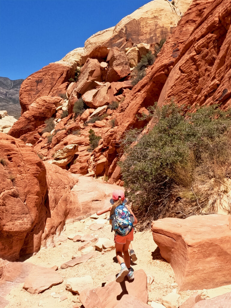 calico tanks trail girl walking through red rock hiking trail with large boulders
