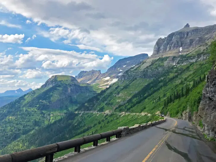 road trips USA view of road cutting through massive mountainside on cloudy day