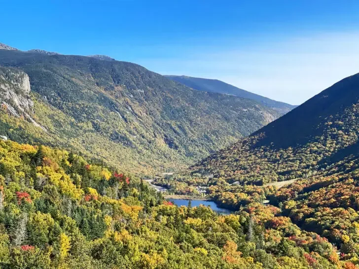 lush valley with green and a few red trees with lake at base best places to visit in August