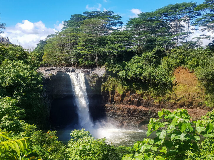 where to travel in August view of Rainbow falls in Big Island Hawaii water falling into pool with lush greenery surrounding