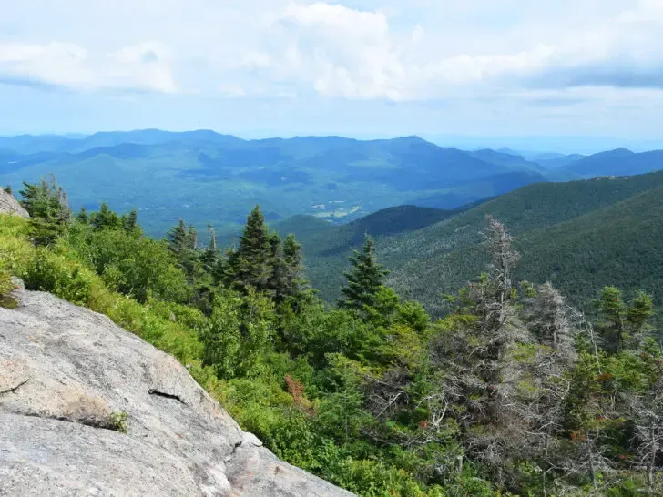 best place to visit in August view of mountains near Lake Placid New York with stone overlooking green mountains