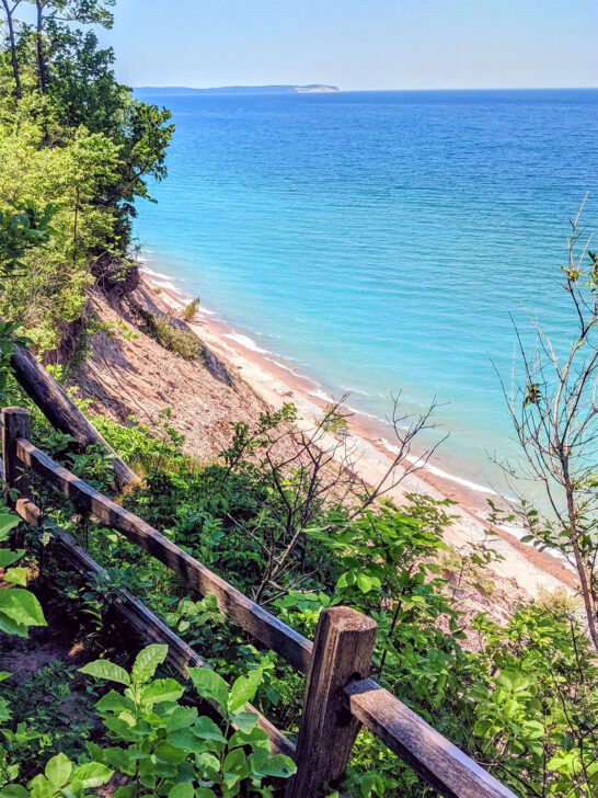 best places to visit in August view of railing and beach with blue water in Michigan