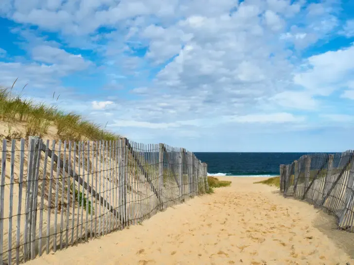 best places to travel in august view of sand and beach fence leading to ocean