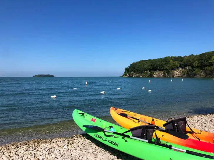 august vacation destinations view of kayaks on shore of Lake Erie Ohio with coastline and blue sky