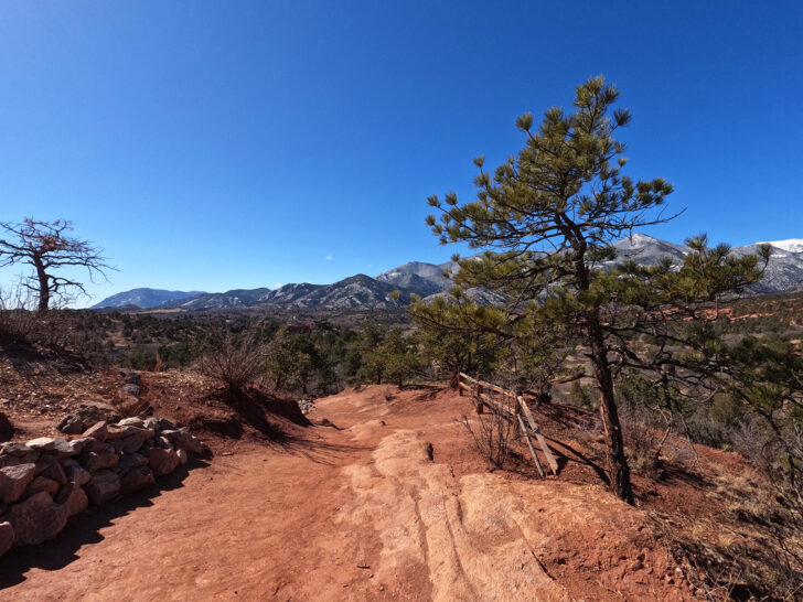red dirt hiking trail colorado with trees and mountains in distance