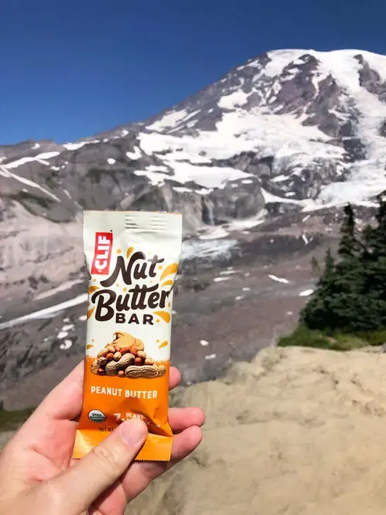 holding clif nut butter bar with mount rainier national park in distance