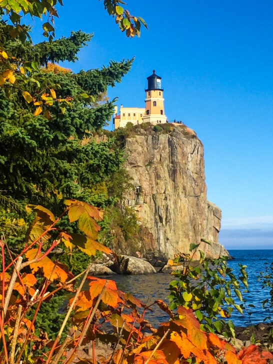 fall drives view through orange foliage of lighthouse on cliffside