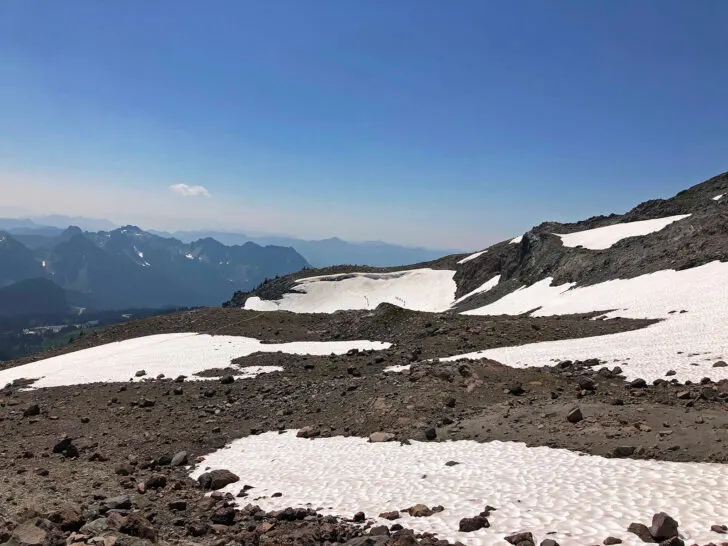 snow patches on dirt with mountains in distance