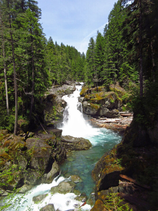 best hikes in mt rainier national park view of waterfall through trees with rocky surround