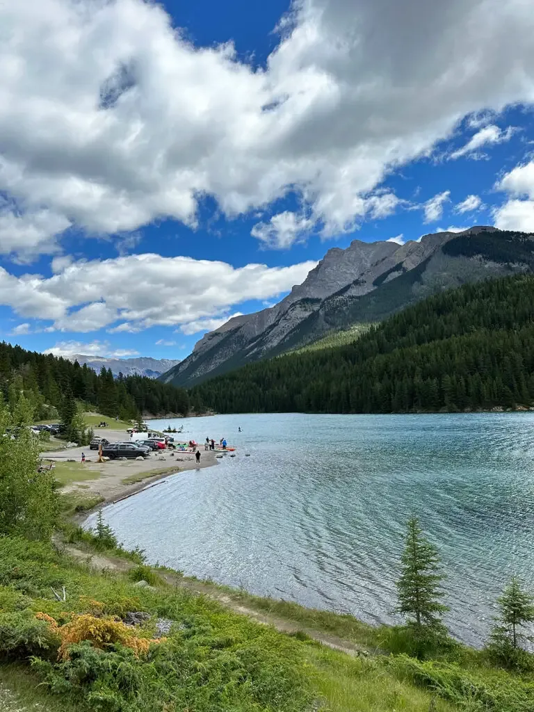 lakeshore on sunny day with mountains and white puffy clouds