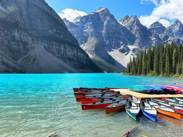 Banff summer view of kayaks on blue lake with mountains in distance in Alberta Canada