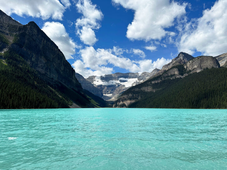 bright teal water with mountains in distance view of Banff summer at Lake Louise