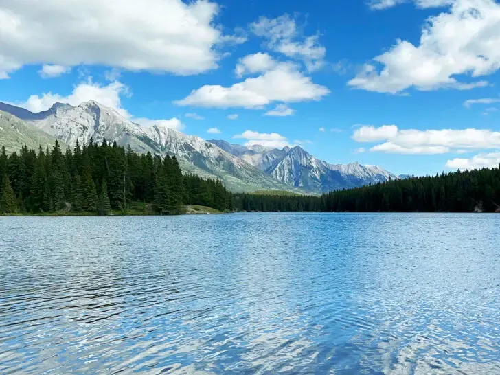 Banff things to do summer view of lake with trees and mountains in distance on sunny day