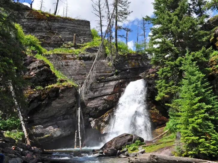 waterfall hikes in glacier national park view of waterfall from cliff with trees and rocky side