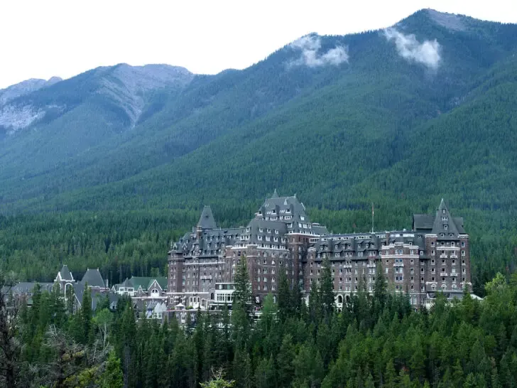 castle in mountains with trees surrounding it