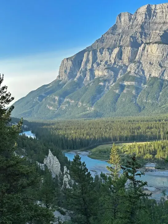 large mountain in distance with white jagged rocks at base and river