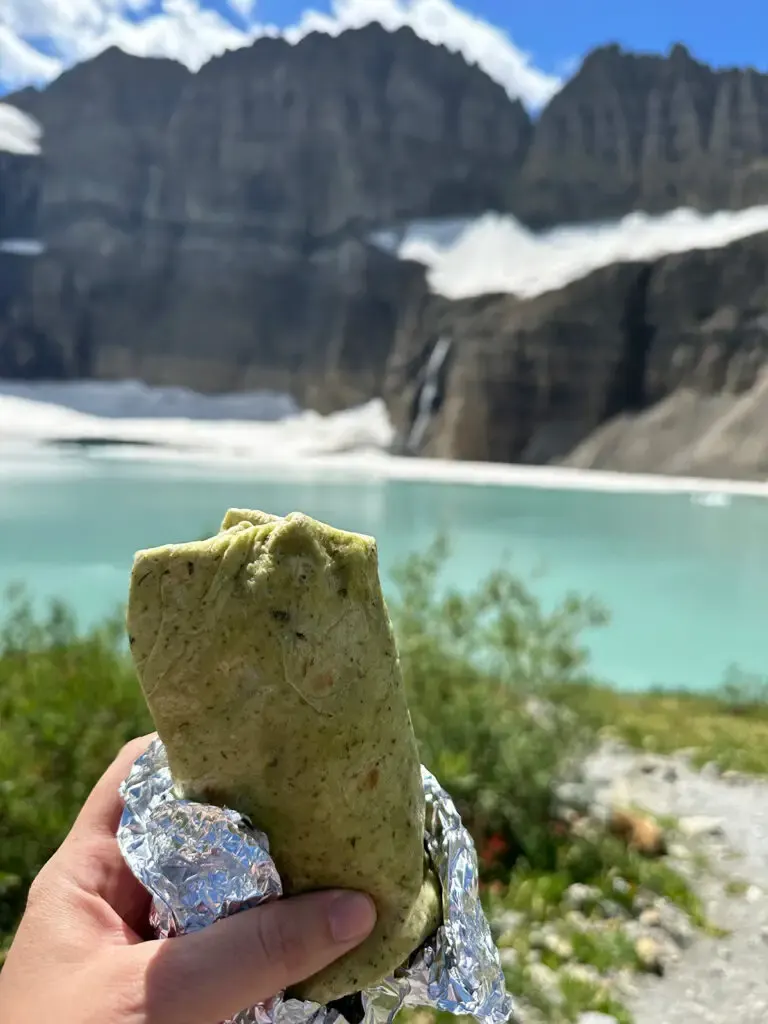 hand holding sandwich wrap with lake in distance