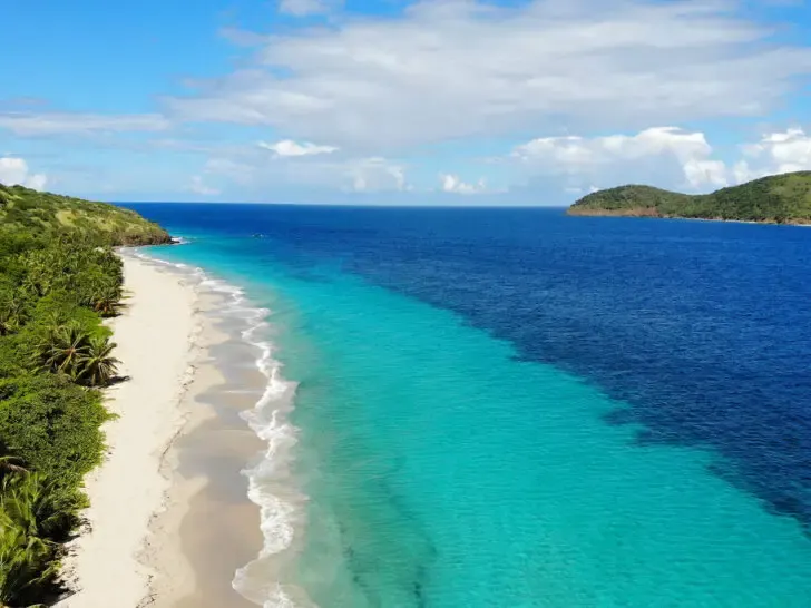 best places to visit in November USA view of beach from above with palm trees teal and blue water with white sand