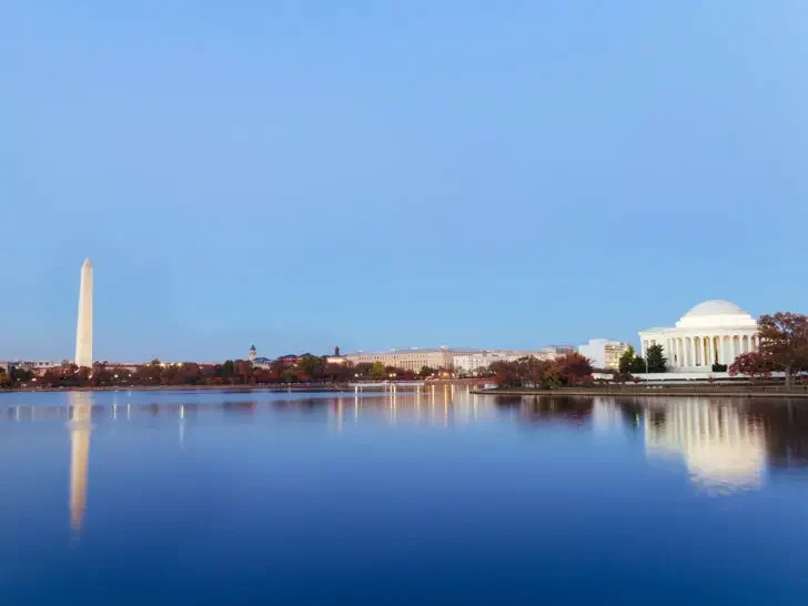 lake and monuments in Washington DC with red trees at dusk