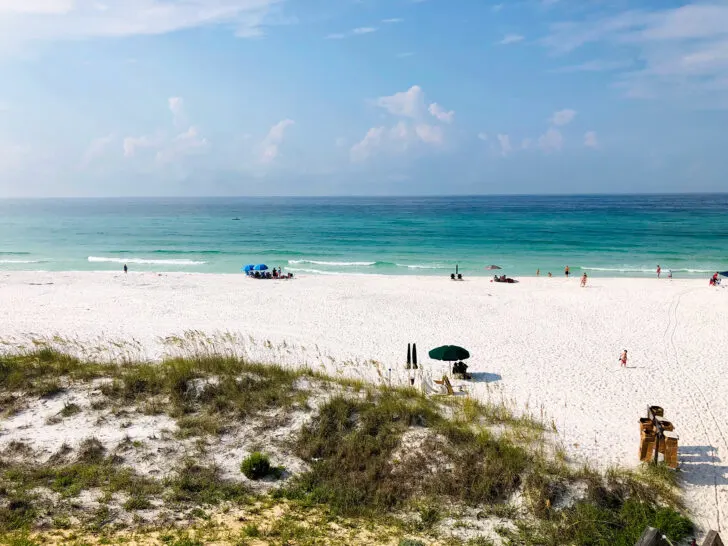 warm winter vacations in the US view of beach and sand dune with teal water and people near waters edge