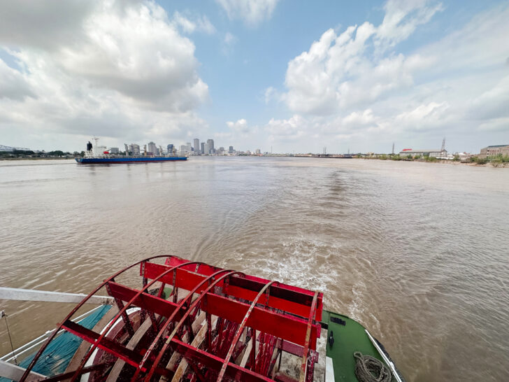 view of wide river with back of boat up close and city on New Orleans in distance