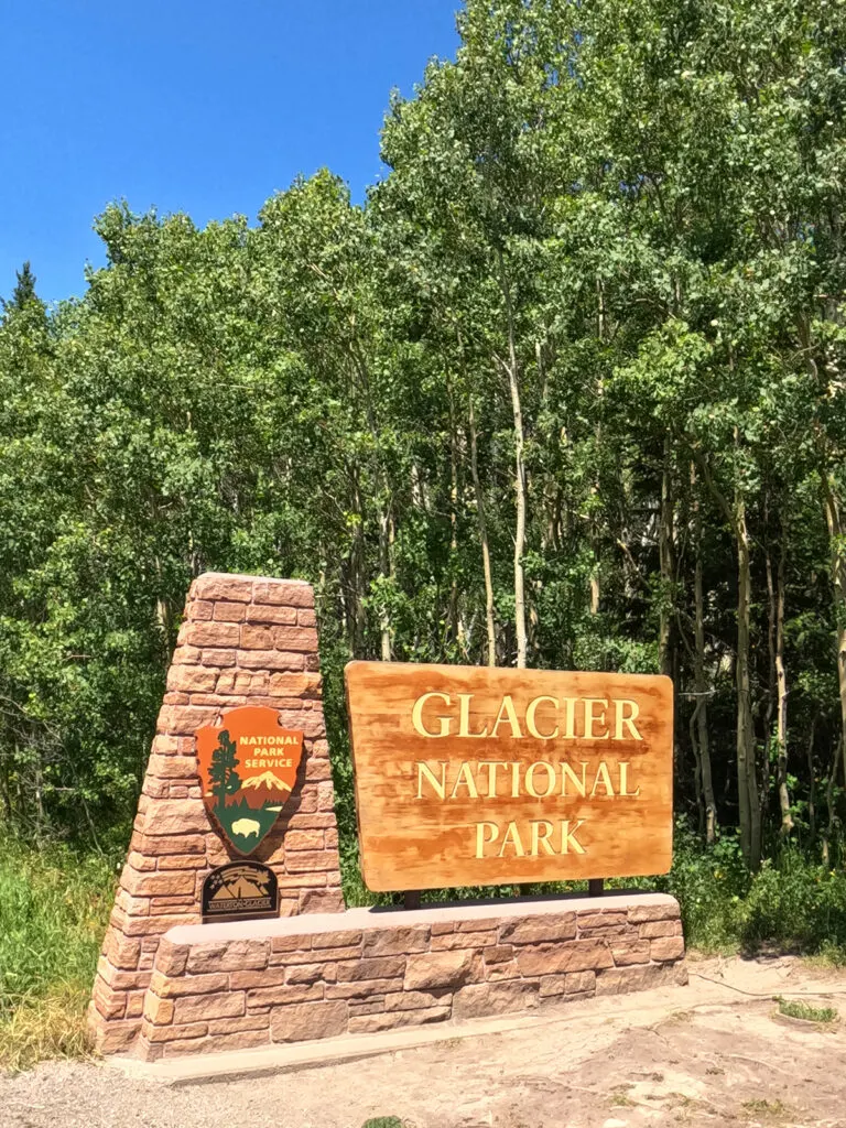 glacier national park sign at two medicine entrance with trees behind