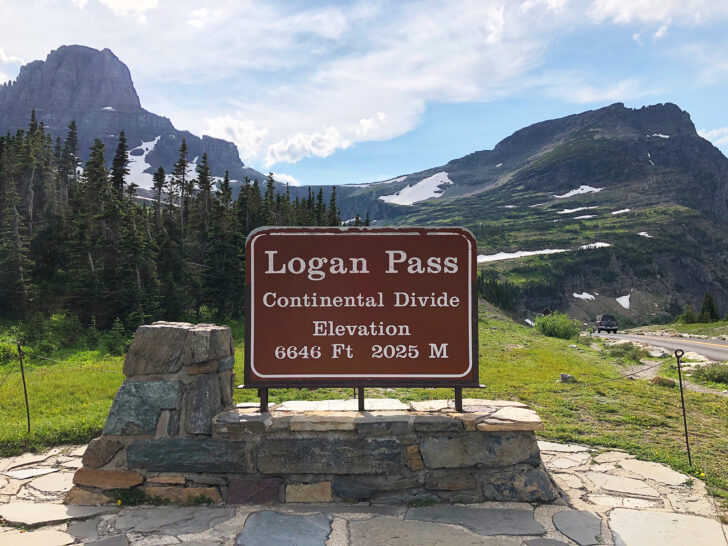 sign reads Logan pass continental divide elevation 6646ft 2025m with mountains behind