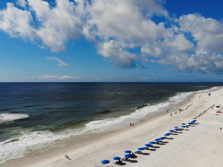 warm winter vacations USA view of gulf shores beach with waves umbrellas on sand and sunny sky
