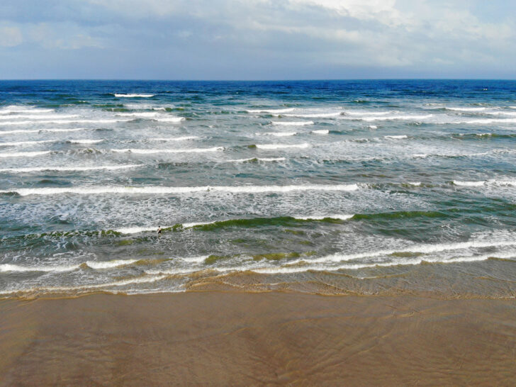 beach with deep ocean waves white caps and tan sand