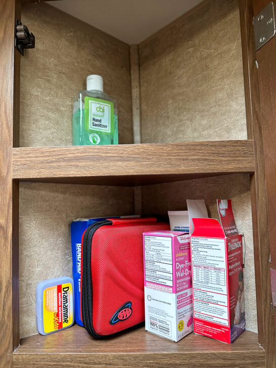 inside view of medicine cabinet with first aid kit and kids medications RV camping list