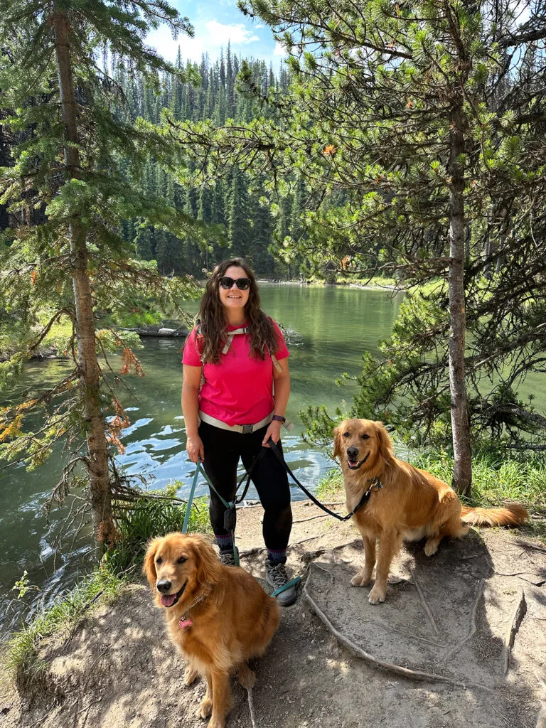 woman hiking with dogs with trees and nature behind