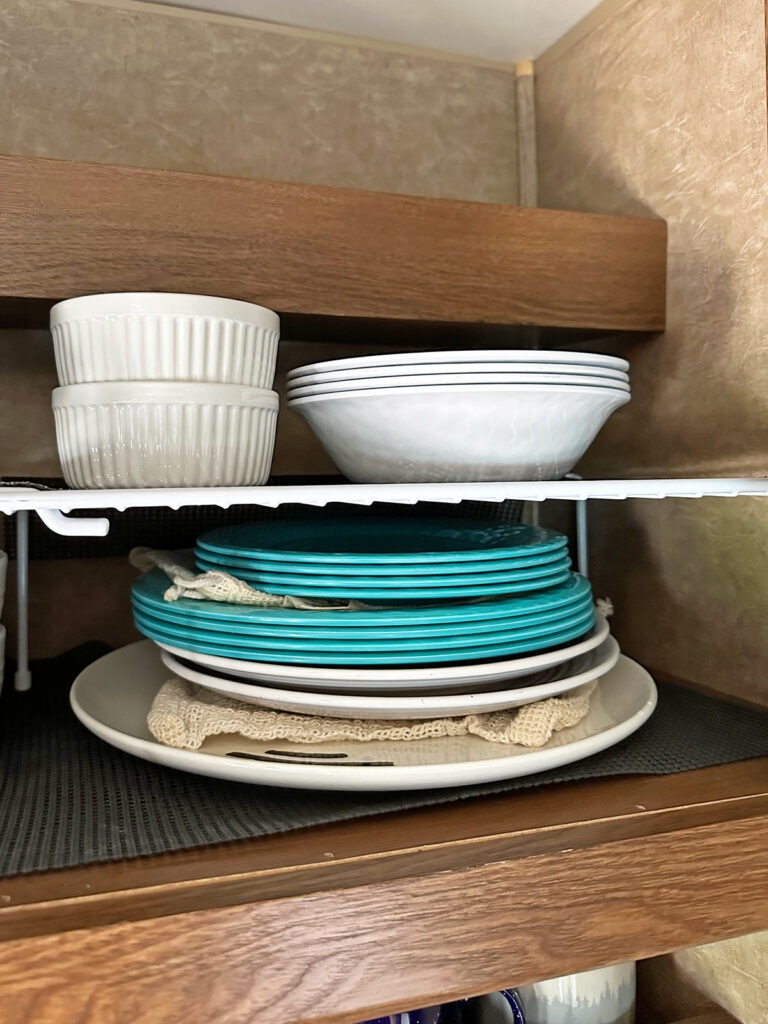 plates and bowls stacked in cabinet with dividers and non-slip mats best camper tricks