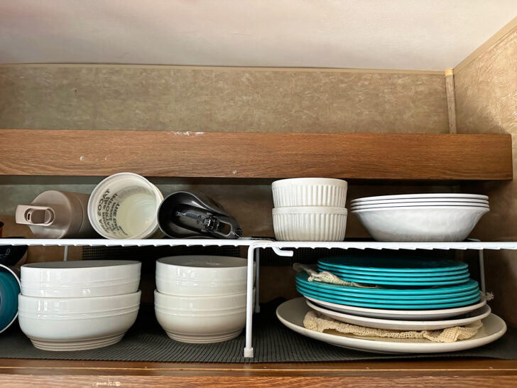 plates and bowls stacked in cabinet with vertical divider