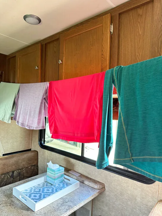 shirts hanging on a clothesline inside a camper over a table