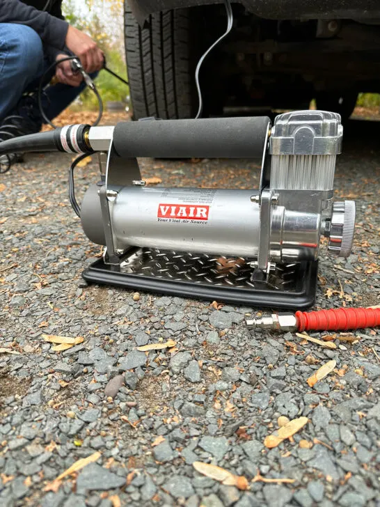 air machine sitting on ground with man kneeling by tire in distance